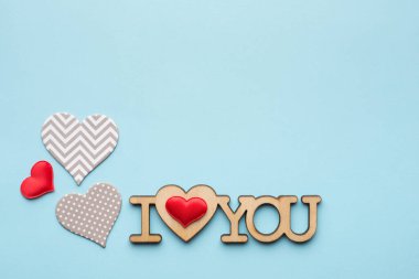 Gri ve kırmızı kalpler, şablonlar ve ahşap. Mavi arka plan manzaralı harfleri seviyorum. 14 Şubat 'ta Sevgililer Günü konsepti