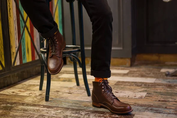 Mann Sitzt Auf Barstuhl Braunen Lederstiefeln Auf Retro Hintergrund — Stockfoto