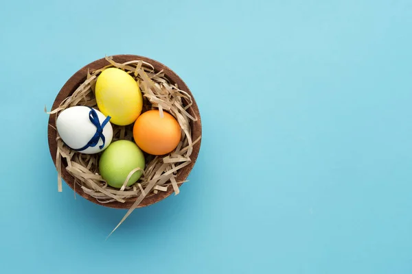 Malovaná Velikonoční Vajíčka Kulatém Dřevěném Talíři Řemeslnou Seno Modrém Pozadí — Stock fotografie