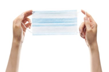 Beyaz arka planda virüsten korunmak için kadın elleri tıbbi maske tutuyor.