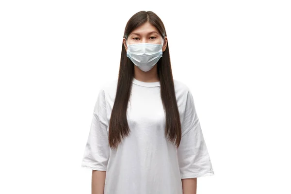 不幸な若いですアジアの女の子で医療マスク上の白い背景孤立 — ストック写真