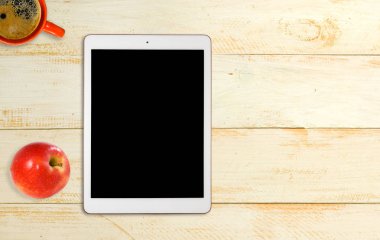 bir fincan kahve, tablet ve ahşap bir masa üzerinde bir elma görüntüsünü