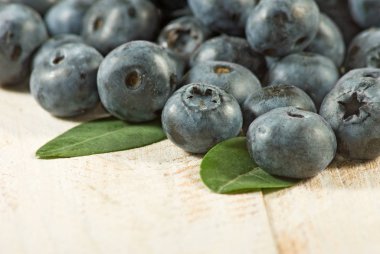Ahşap bir yüzey üzerinde yaprakları ile yaban mersini grubu.