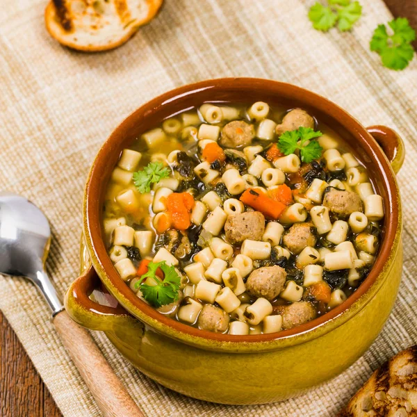 Traditional Italian-Style Wedding Soup. Made with Meatballs, Carrots and Spinach in Chicken Broth. Selective focus.