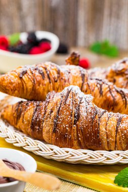 Eski ahşap zemin üzerine olgun çilek ile çikolatalı kruvasan. Seçici odak.