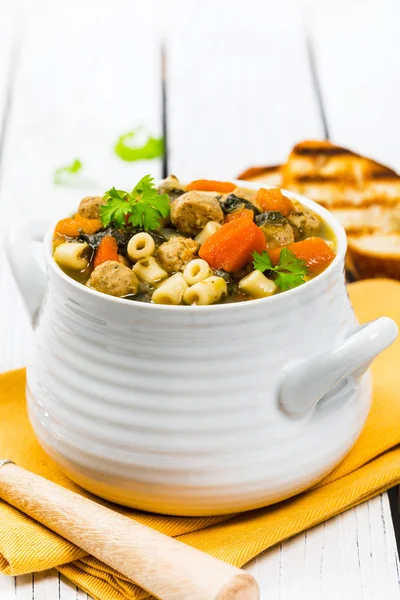 Traditional Italian-Style Wedding Soup. Made with Meatballs, Carrots and Spinach in Chicken Broth. Selective focus.