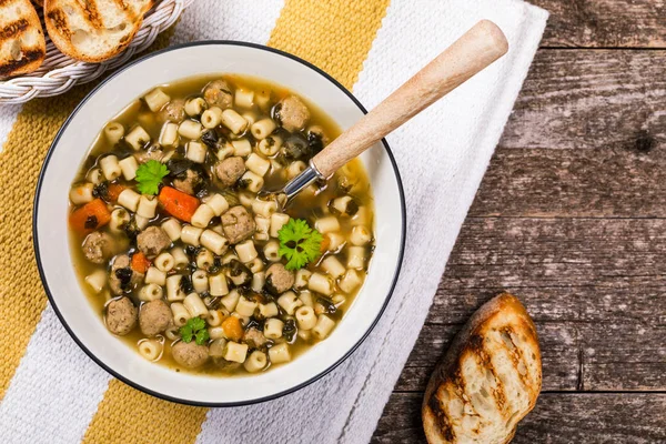 Traditional Italian-Style Wedding Soup. Made with Meatballs, Carrots and Spinach in Chicken Broth. Selective focus.