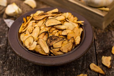 Ahşap zemin üzerine kavrulmuş sarımsak dilimleri. Seçici odak.