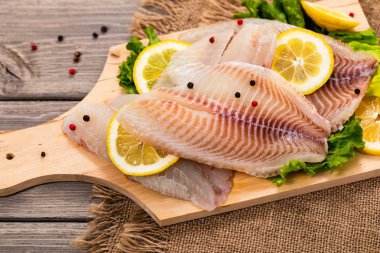 Ahşap arka planda Whitefish Tilapia balık RAW fileto. Seçici odak.
