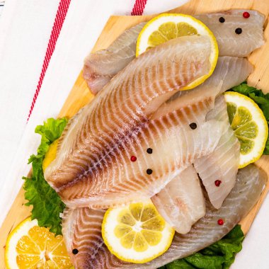 Beyaz ahşap arka planda Whitefish Tilapia balık RAW fileto. Seçici odak.