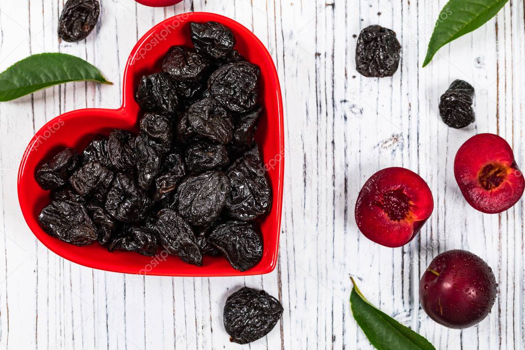 Dried Plums Pitted Prunes in Heart Shaped Bowl Background. Selective focus.