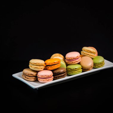 Renkli Makaronlar Çikolata, Şam fıstığı, Kiraz, Turuncu, Vanilya arkaplan ve Siyah Arkaplan. Seçici odak.