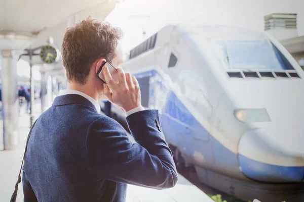 ビジネス旅行 モバイルの駅 電車を待っている間に電話で話しているビジネスマンを呼び出す — ストック写真