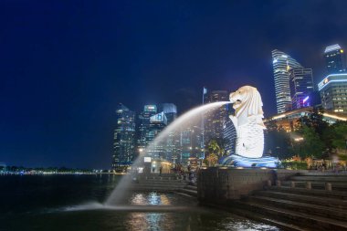 Singapur - 06 Eylül 2016: Gece sahne ışıklı Merlion Çeşme ve arka plan üzerinde modern iş binaları