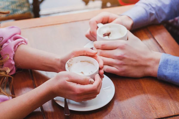 people drinking coffee in cafe, closeup of couple hands with cups