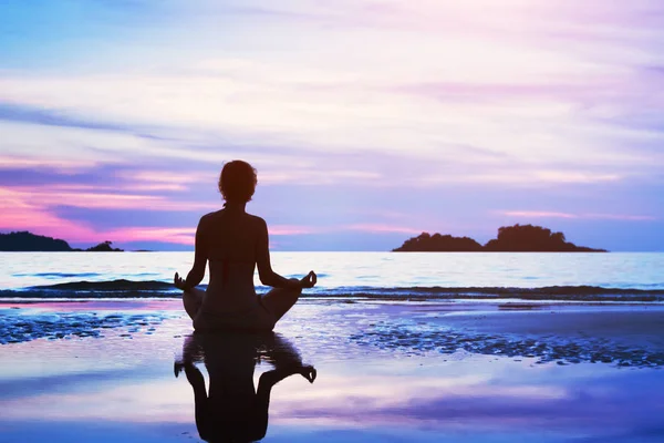 美しいヨガ背景 夕暮れ時のビーチで瞑想の女性のシルエット — ストック写真