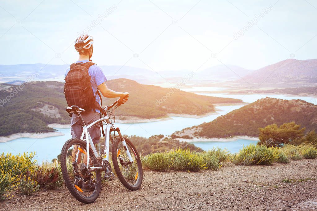 cycling, mountain biking, man with bicycle enjoying panoramic view at sunset