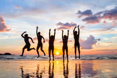 bir grup insan mutlu arkadaş günbatımı, siluetleri plaj tatil günlerinde atlama