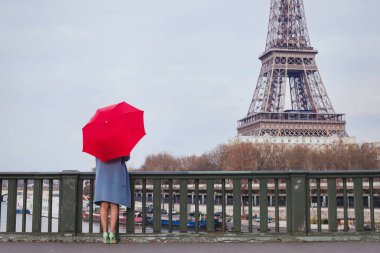 Kırmızı şemsiye ayakta Eyfel Kulesi Paris, Fransa'da manzarasında köprüde kadınla
