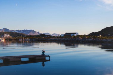 Yoga ve meditasyon arka plan, adam göl kenarında iskelede rahatlatıcı silüeti