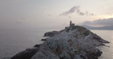 Portoferraio, Elba Adası (İtalya önünde bitki örtüsü olmadan kayalık bir adacık zirvesinde bir deniz feneri şafakta havadan görünümü)