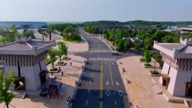 Banliyö bölgesinde açık bir günde yeşilliklerle çevrili geniş bir yolun yüksek açılı görüntüsü