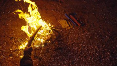 Adam şenlik ateşine odun koyuyor.  