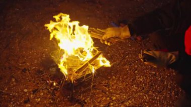 Adam şenlik ateşine odun koyuyor.  