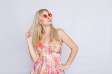 çiçekli pembe elbise ve parlak pembe güneş gözlüğü uzun saçlı Genç sarışın bir kadın portresi