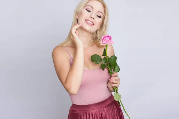 一个可爱的年轻金发女郎拿着粉红色的玫瑰 — 图库照片