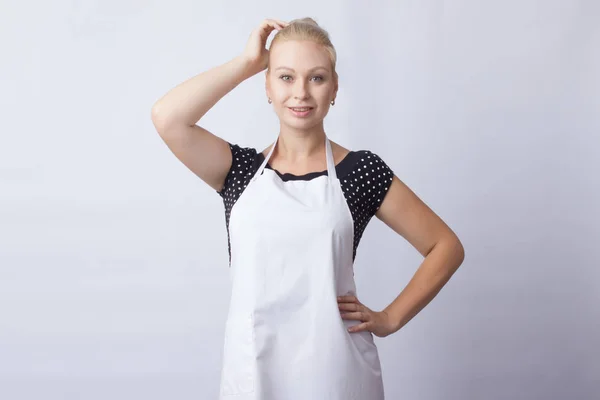 cute blonde woman in white apron posing on white background. cook. a housewife