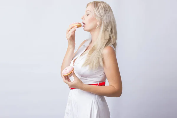 Молодая Блондинка Белом Платье Держит Руках Розовых Пончика Глазурью — стоковое фото