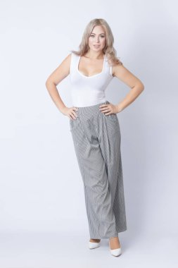 Duran neşeli sarışın kadın portresi tam uzunlukta kameraya bakıyor. Gri arka plan üzerinde izole