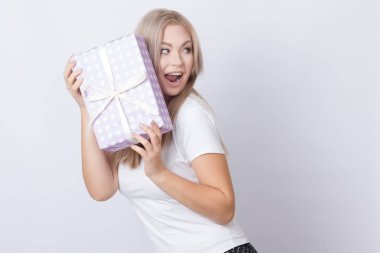 Hediye ile mutlu sevimli sarışın kadın kutu onun elinde gri arka plan üzerinde