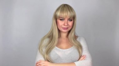 Çapraz kolları üzerinde açık gri renkli Studio izole olan gri t-shirt ayakta giyen çekici sarışın kadın