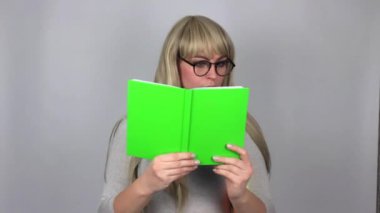 Holding ve Studio gri arka plan üzerinde izole kitap okuma beyaz sarışın kadın