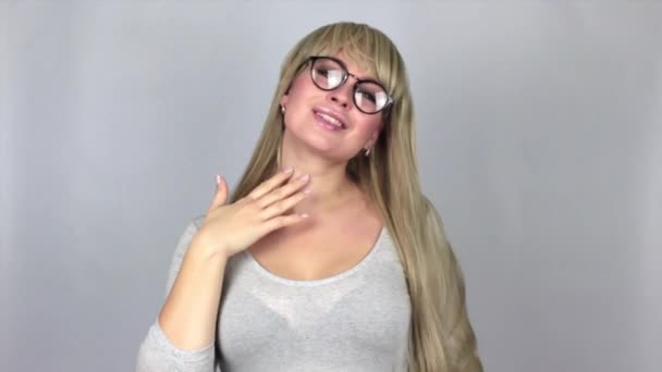 Блондинка Показує Щось Над Сірим Тлом Студії — стокове відео