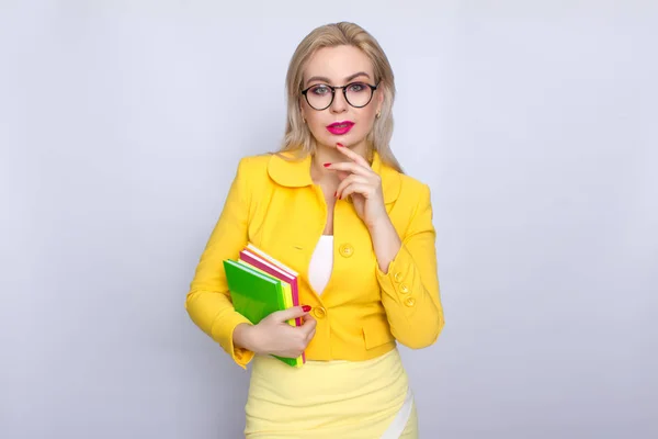 Mulher de terno amarelo segurando livros em suas mãos — Fotografia de Stock