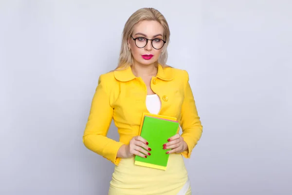 Mulher de terno amarelo segurando livros em suas mãos — Fotografia de Stock