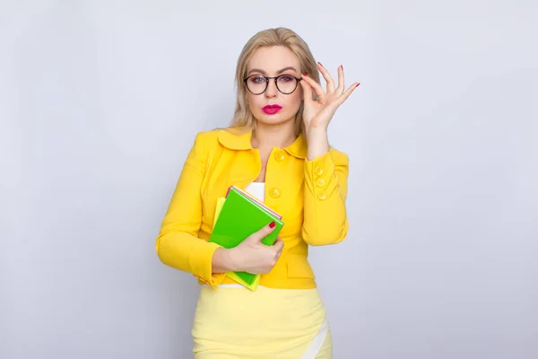 Mulher de terno amarelo segurando livros em suas mãos — Fotografia de Stock