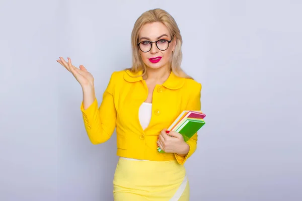 Женщина в жёлтом костюме держит книги в руках — стоковое фото