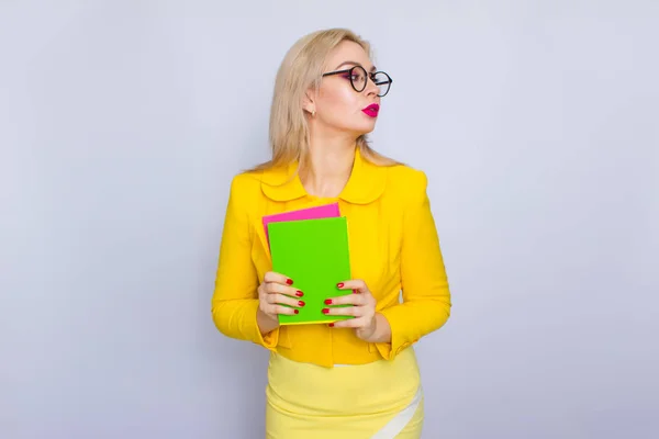 Mulher de terno amarelo segurando livros em suas mãos — Fotografia de Stock