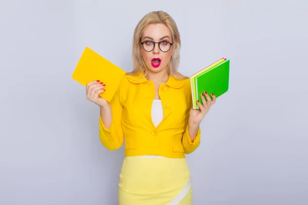 Mulher de terno amarelo segurando livros em suas mãos — Fotografia de Stock