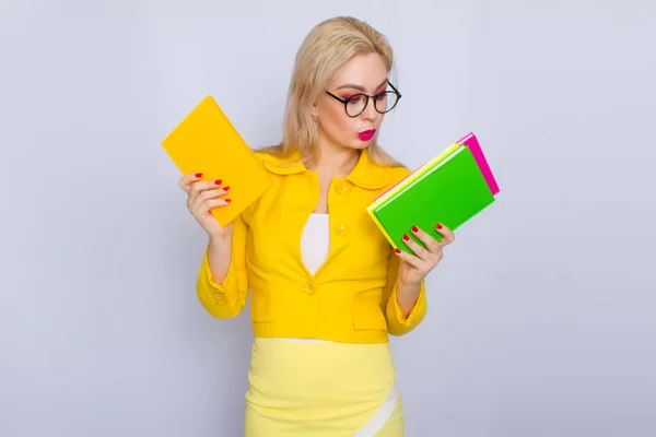 Женщина в жёлтом костюме держит книги в руках — стоковое фото
