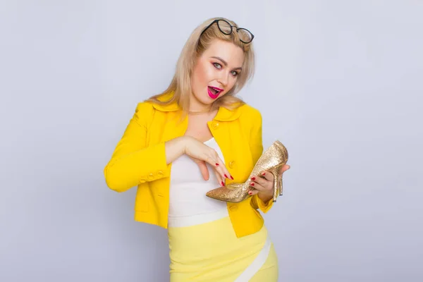 Glamour mujer rubia sosteniendo zapatos de oro —  Fotos de Stock