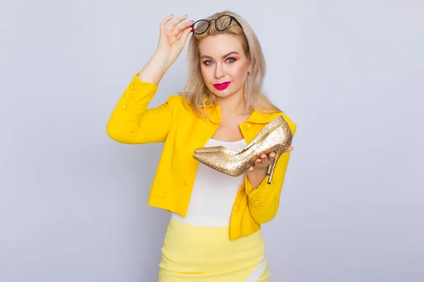 Mulher loira glamour segurando sapatos de ouro — Fotografia de Stock