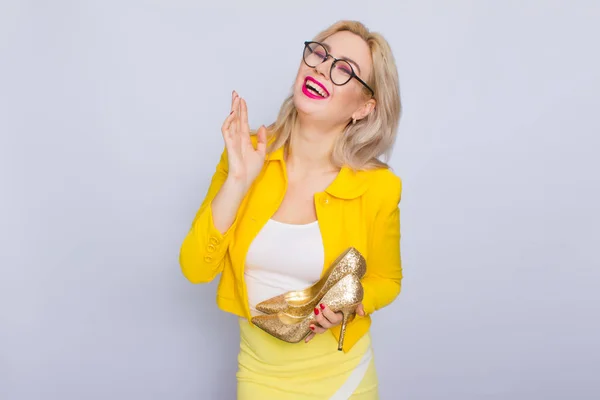 Mulher loira glamour segurando sapatos de ouro — Fotografia de Stock