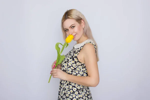 Mujer rubia sosteniendo un tulipán amarillo — Foto de Stock