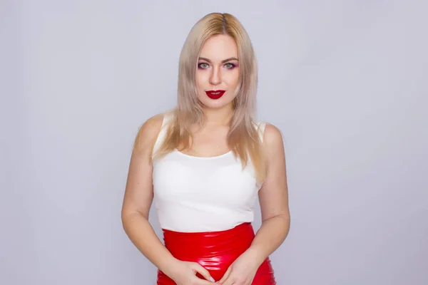 Blond kobieta w czerwonej skórzanej spódnicy i białej koszulce — Zdjęcie stockowe