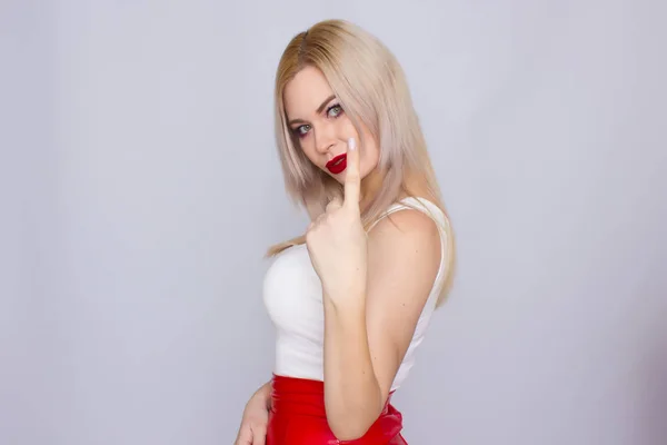 Blond kobieta w czerwonej skórzanej spódnicy i białej koszulce — Zdjęcie stockowe